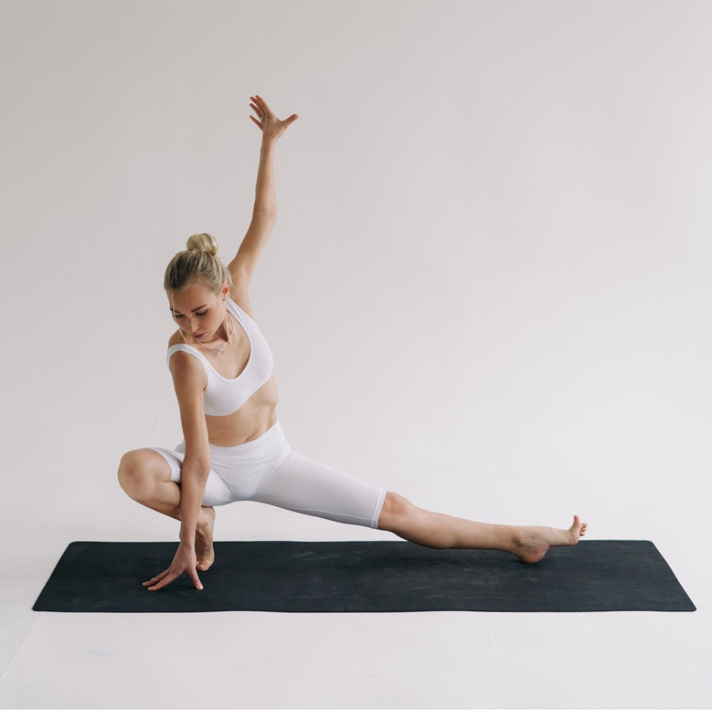 Kvinde laver yoga på en sort træningsmåtte
